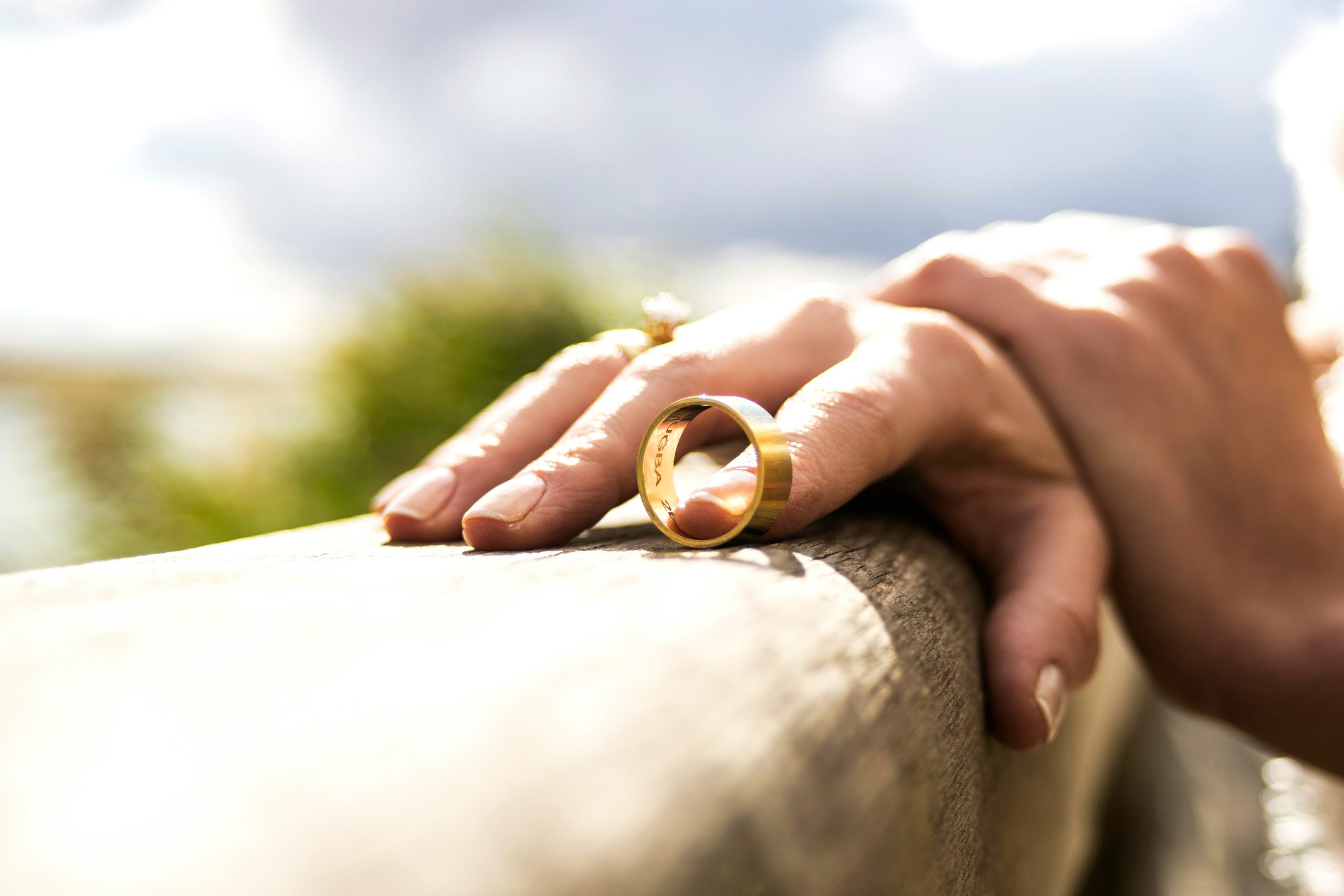 A woman's hand delicately holds a gold wedding ring, symbolizing love and commitment.