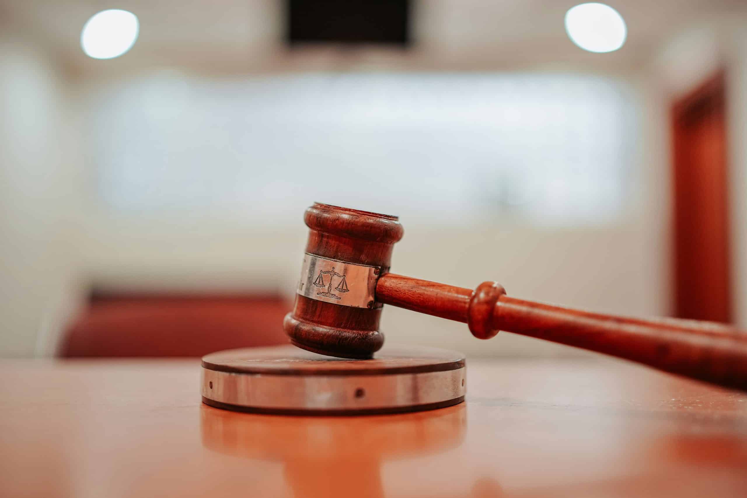 Judge's gavel resting on a wooden table in a courtroom, symbolizing authority and legal proceedings.