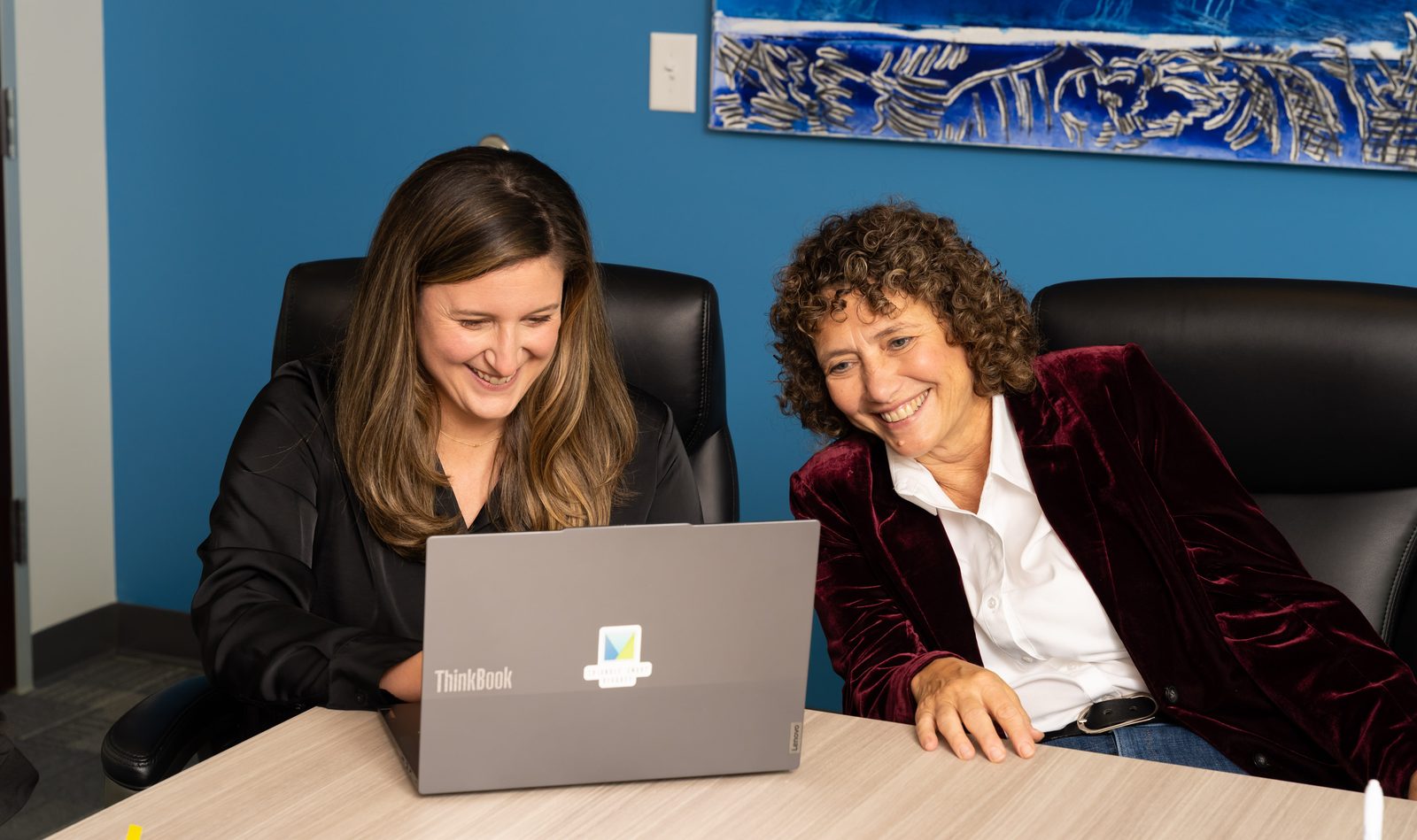 Lisa LeFante and Diane Allen of Triangle Smart Divorce smiling as they review work together on a laptop in the firm’s conference room
